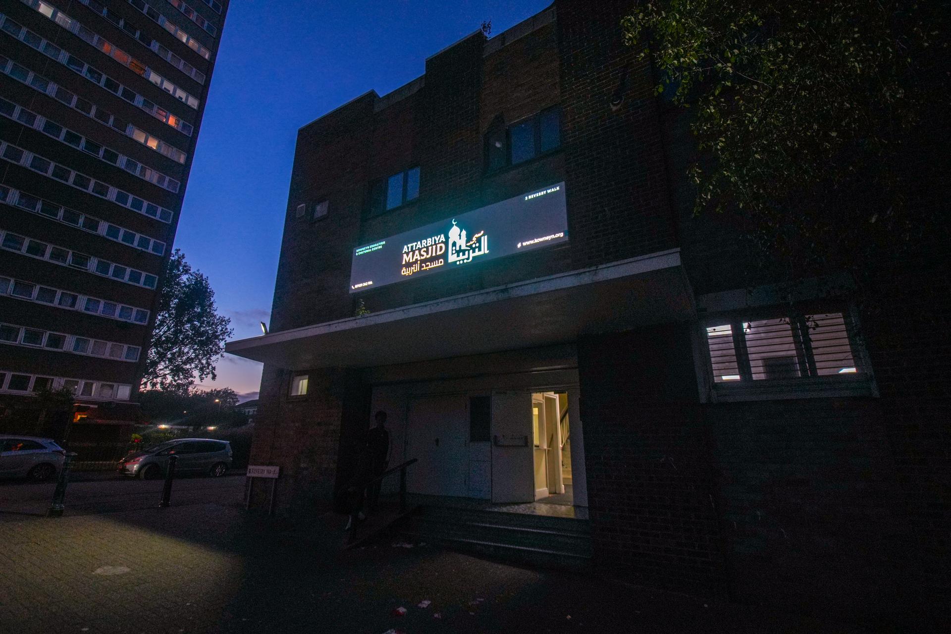 The masjid at dusk, its sign lit above the entrance on Revesby Walk
