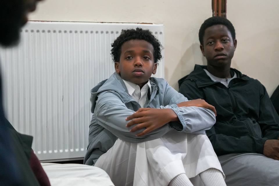 Two boys sitting by a radiator, listening