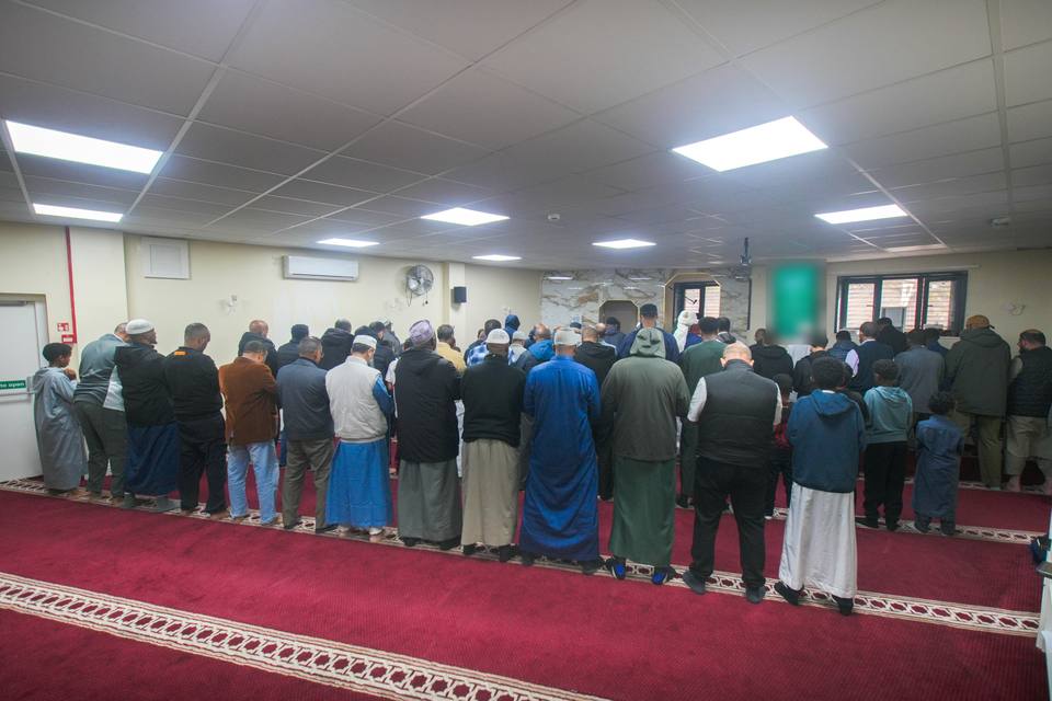 The congregation standing in rows for Dhuhr, seen from behind