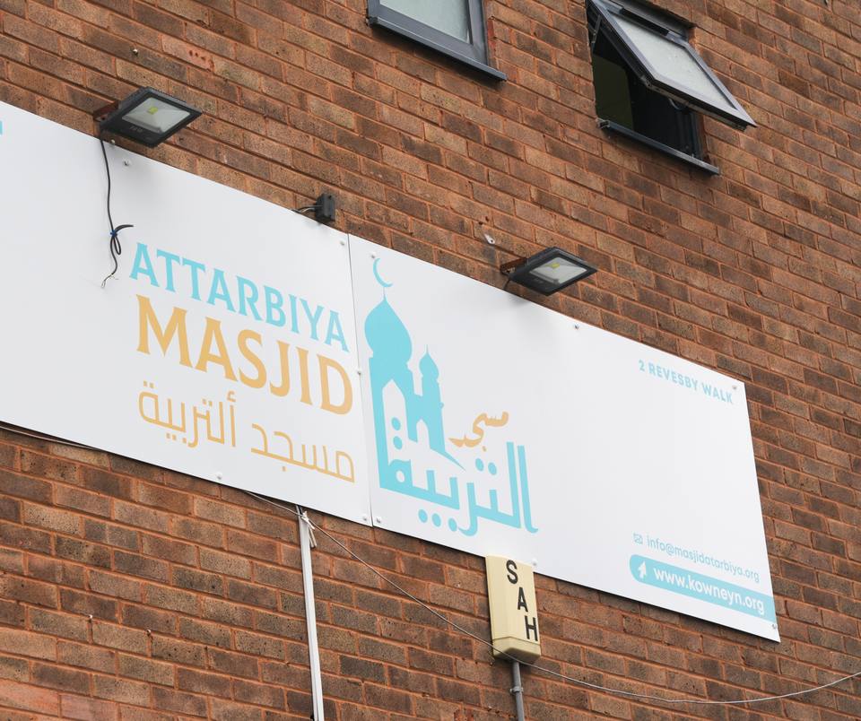 The masjid's sign on the brick wall: Attarbiya Masjid in English and Arabic