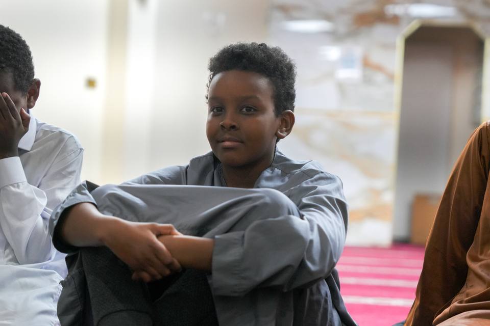 A boy sitting with his arms round his knees, smiling