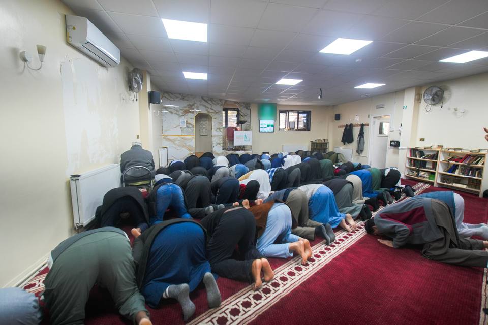 The congregation in sujud, foreheads to the red carpet