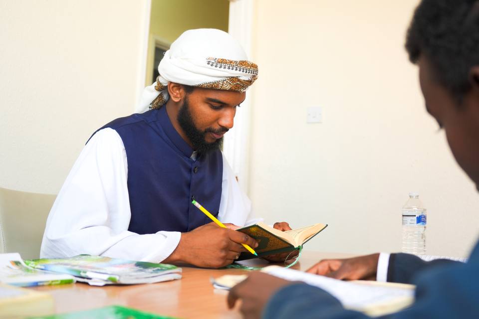 A teacher reading at a table, pencil in hand