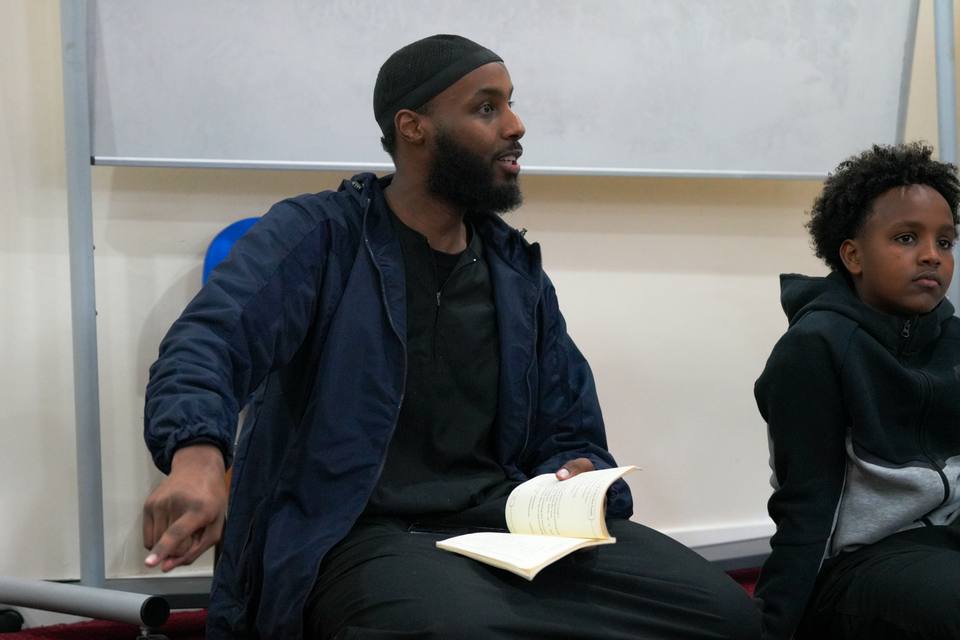 The teacher sitting cross-legged, a book open in his hand