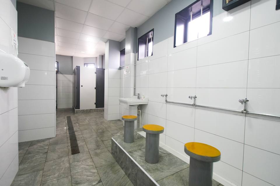 Low round seats with yellow tops in a row beneath the taps of the wudu area