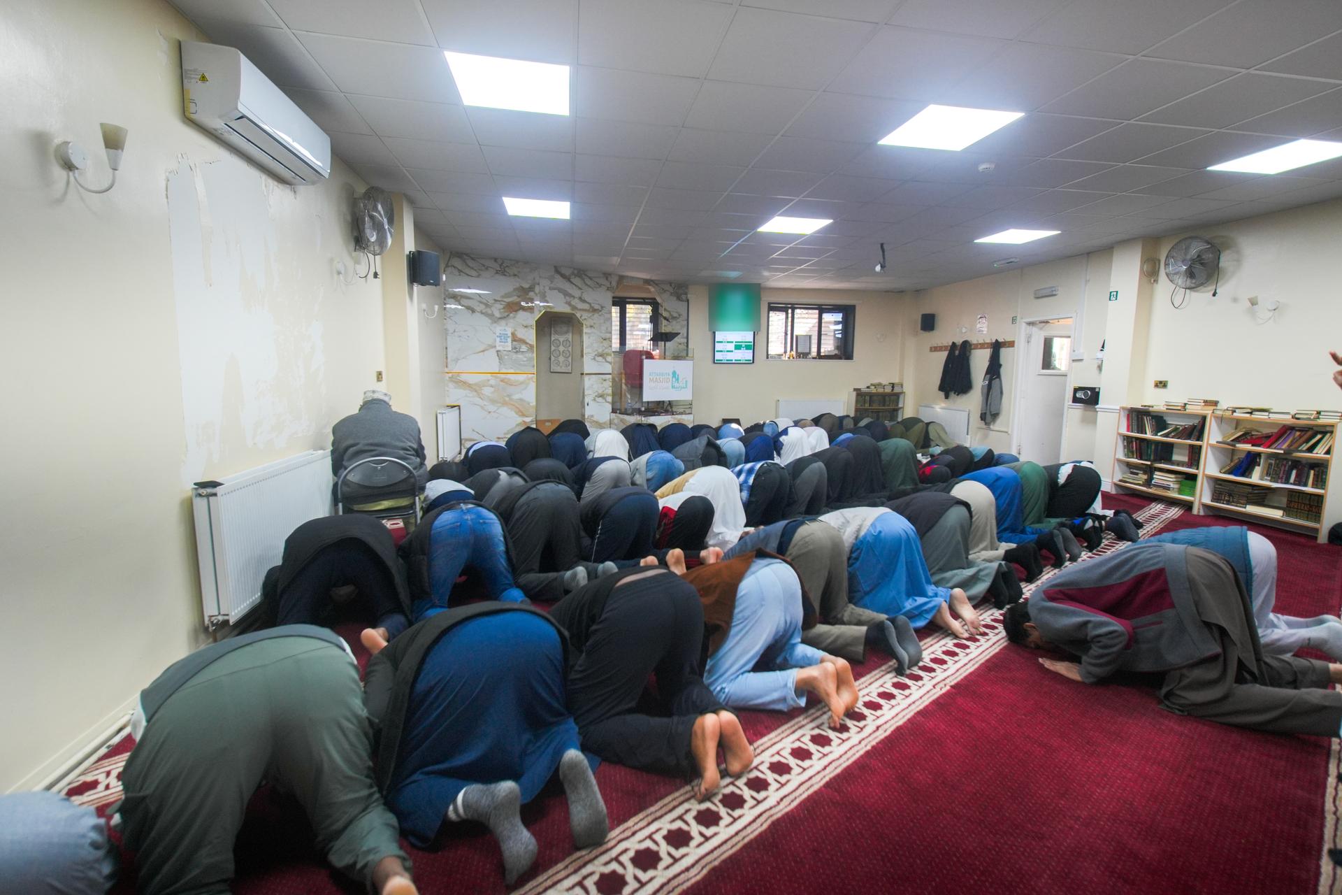The congregation in sujud, foreheads to the red carpet