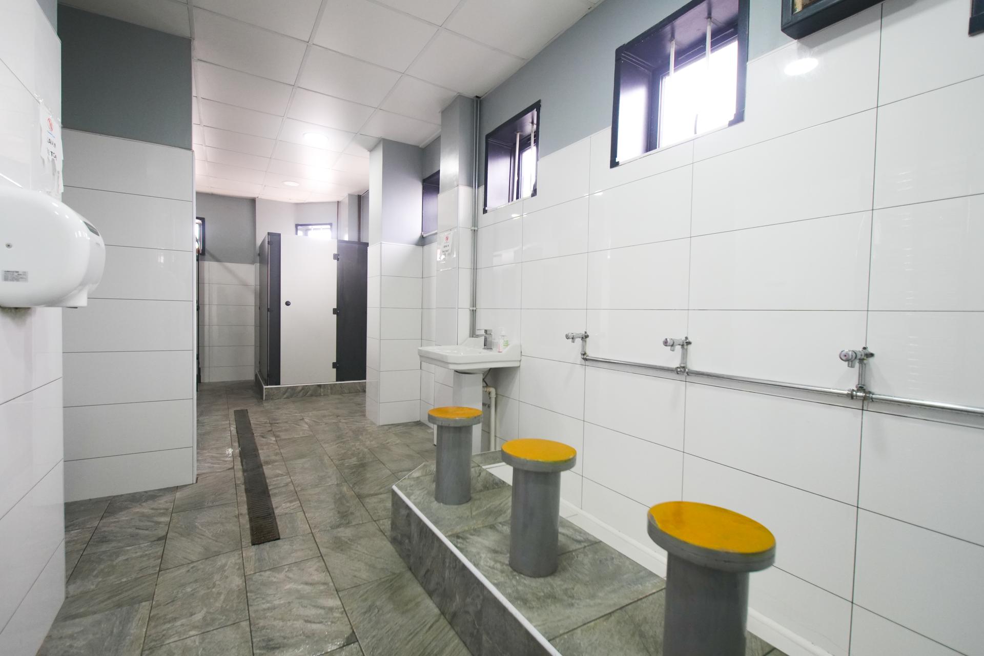 Low round seats with yellow tops in a row beneath the taps of the wudu area